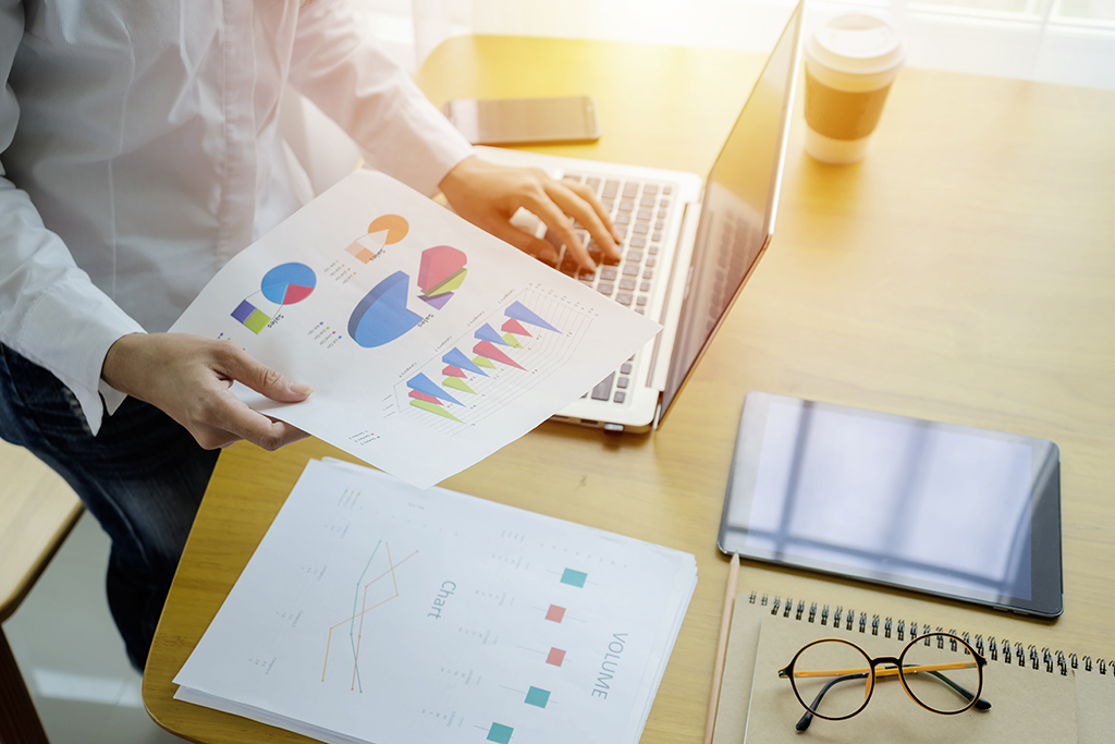 Businessman analyzing investment charts with laptop. working with financial graphs charts online, using business software for data analysis and project management concept, rear close up view.